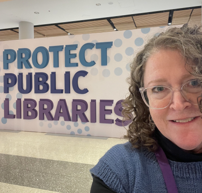library director in front of a sign that says protect public libraries