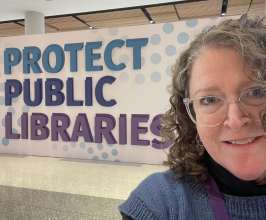 library director in front of a sign that says protect public libraries