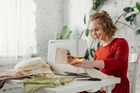 White woman at table with sewing machine and fabric