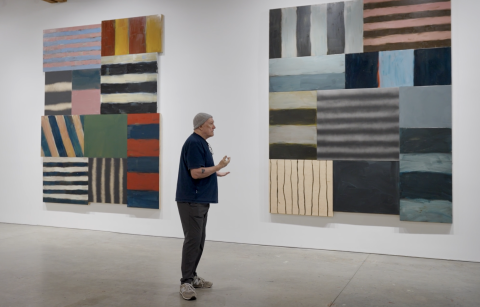 Sean Scully standing in front of his paintings