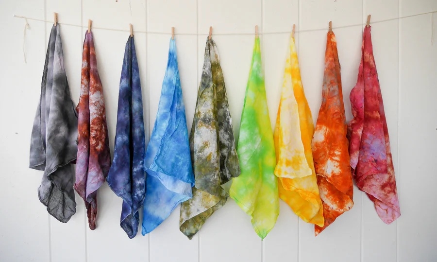 Tie dye bandanas hanging from a clothesline in rainbow order