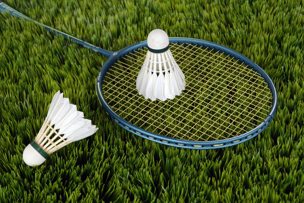 Badminton racket and two birdies on grass